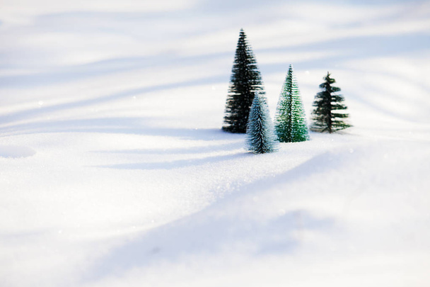 Small artificial christmas trees on soft snow - Foto, imagen