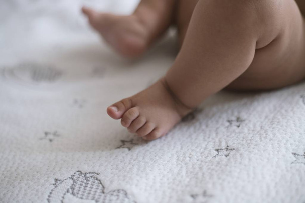 A closeup shot of a newborn baby's cute little feet on a star-patterned white blanket - Photo, image