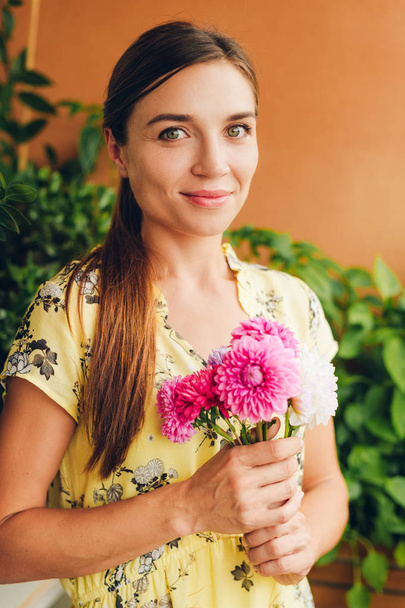 Romantic portrait of beautiful young woman with small bouquet of colorful chrysanthemum flowers - Photo, Image