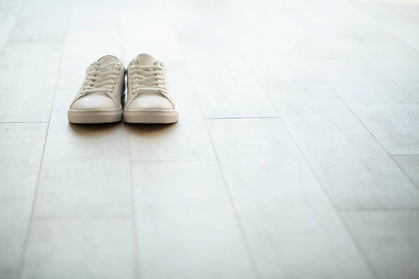 Pair of new stylish white sneakers on floor at home - Photo, Image