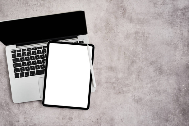 Open laptop with digital tablet on grey concrete background. - Foto, Bild