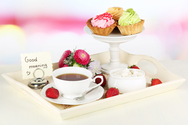 Cup of tea with cakes on wooden tray on table in room - Foto, afbeelding