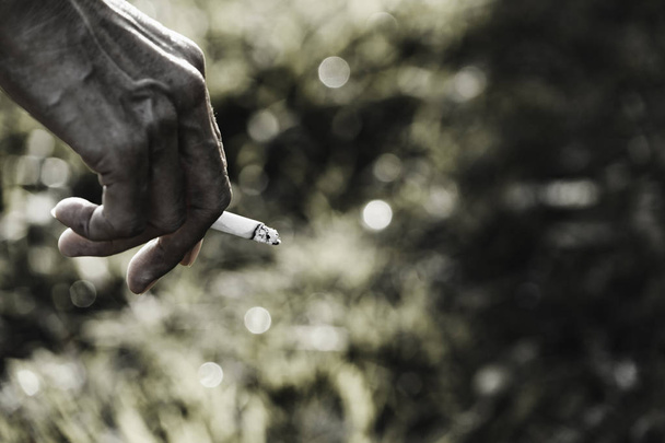 Uma mão a segurar um cigarro. Um homem fumando um cigarro e copiar spa
 - Foto, Imagem