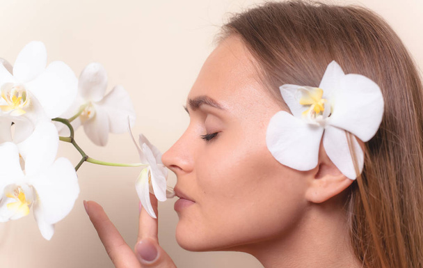 Closeup portrait of a beautiful model with white orchid flowers. - Foto, Imagem