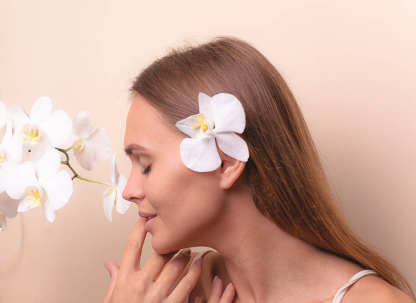 Close-up portret van een mooi model met witte orchidee bloemen. - Foto, afbeelding