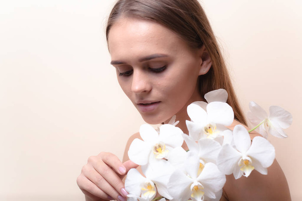 Κοντινό πορτρέτο ενός όμορφου μοντέλου με λευκά λουλούδια ορχιδέα. - Φωτογραφία, εικόνα