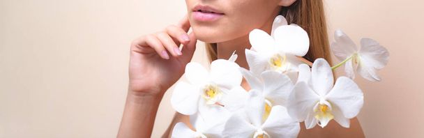 Zbliżenie portret pięknego modelu z białym orchidei kwiatów. - Zdjęcie, obraz