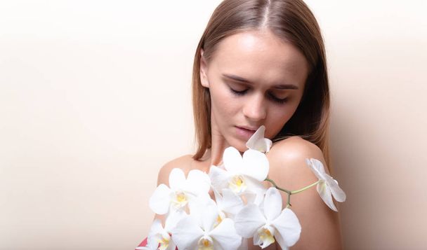 Closeup portrait of a beautiful model with white orchid flowers. - Foto, afbeelding
