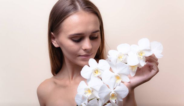 Retrato de primer plano de un hermoso modelo con flores de orquídea blanca
. - Foto, imagen