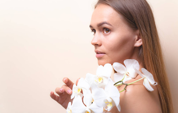 Closeup portrait of a beautiful model with white orchid flowers. - Фото, изображение