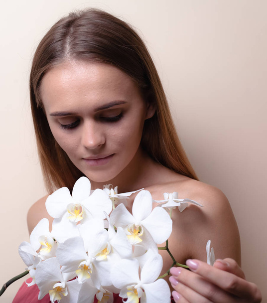 Closeup portrait of a beautiful model with white orchid flowers. - Фото, зображення