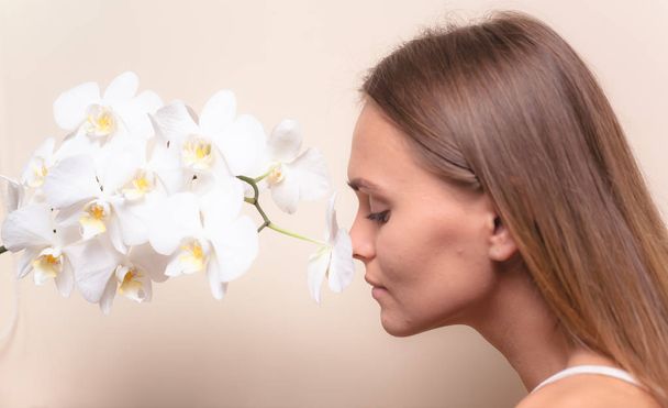 Closeup portrait of a beautiful model with white orchid flowers. - Photo, Image
