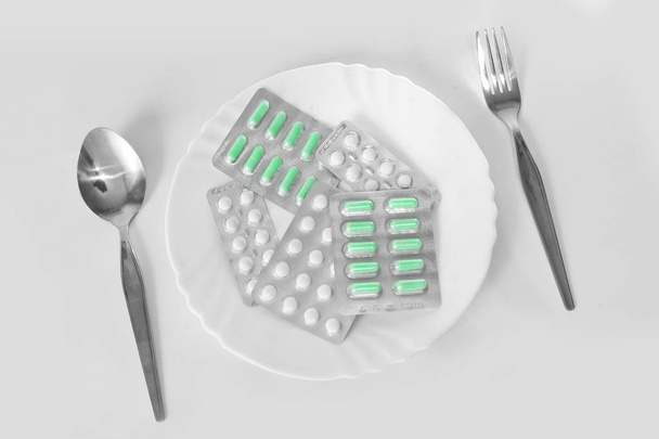 Verschillende pillen op een bord met bestek. Het concept van geneesmiddelen op recept voor gewichtsverlies. Middelen voor het onderdrukken van eetlust. - Foto, afbeelding