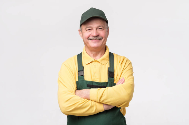 Hispán érett szerelő zöld sapkát és overall állva mosolyogva - Fotó, kép