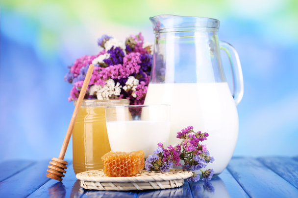 Honey and milk on wooden table on blue background - Valokuva, kuva