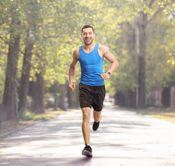 Young guy jogging in a park and smiling - Foto, Imagen