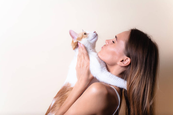 Cute portrait of a girl with a cat. On a light background. - Photo, Image