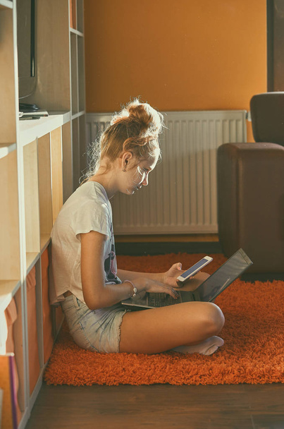 Young woman using portable computer and mobile phone - Foto, Imagen