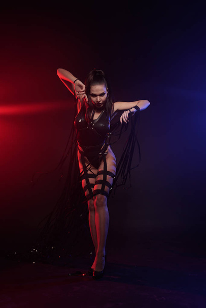 belle course de mélange mince danseuse musculaire fille posant dans un maillot de bain noir avec harnais en cuir avec bandes vidéo
 - Photo, image