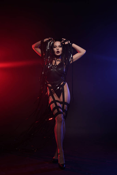 hermosa mezcla de raza esbelta bailarina muscular posando en un traje de baño negro con arnés de cuero con cintas de vídeo
 - Foto, imagen