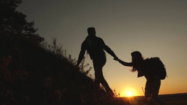 tourists go down from the goy in the sunset, holding hands. male traveler holds the hand of a female traveler going down from top of the hill. teamwork of business people. Happy family on vacation. - Photo, Image