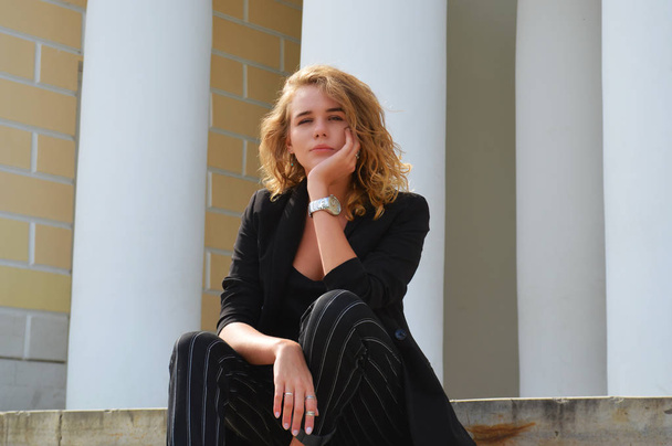 Sexy mladá žena v obchodním černém obleku sedí - Fotografie, Obrázek