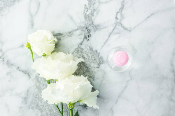Pink transparent spray bottle and flowers on marble - Photo, Image