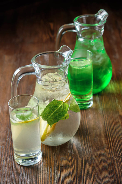 Different soft drinks in transparent jugs on a dark wooden background. menu for catering - Φωτογραφία, εικόνα