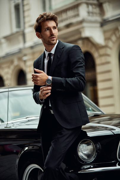 Young handsome man with black classic car wearing black suit  - Fotografie, Obrázek