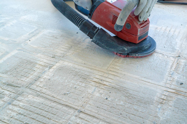stavební pracovník používá betonovou brusku pro sejmutí dlaždic - Fotografie, Obrázek