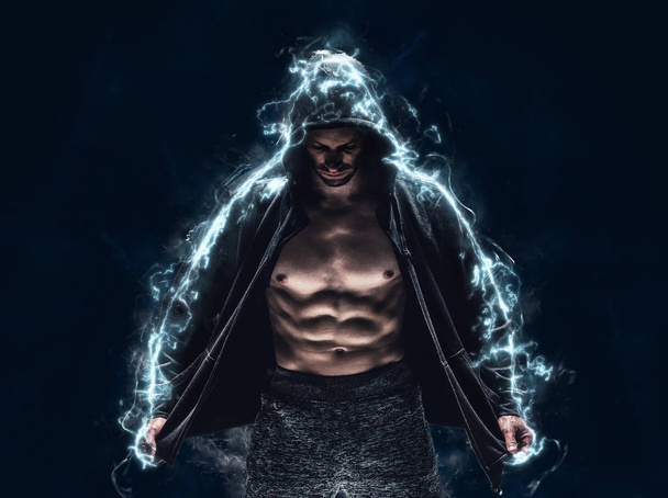 Muscular man in hoodie posing on grey background - Zdjęcie, obraz