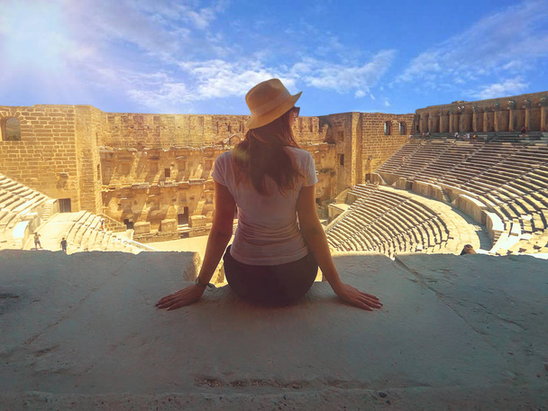 Young beautiful woman in the hat is sitting close up and enjoying the view of Amphitheatre Aspendos in summertime - Foto, Imagem
