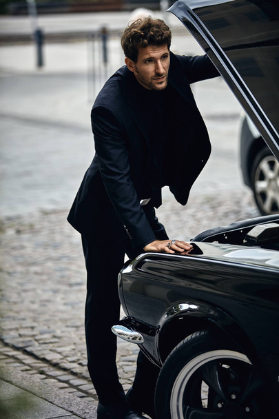 Young man in black suit opened mask and checking engine car - 写真・画像
