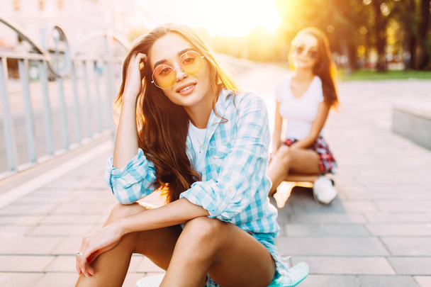 Two stylish young girls sitting with skateboards in the Park - Фото, зображення