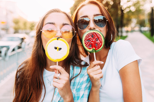 Young stylish funny girls with lollipops have fun in the city in - Фото, зображення