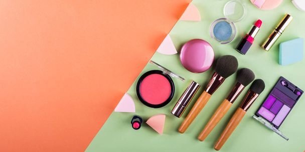 Accessoires de maquillage sur orange et vert. Pose plate
 - Photo, image
