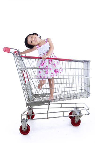Asian girl inside shopping trolley - isolated - Zdjęcie, obraz