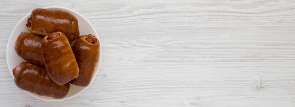 Salsiccia di manzo fatta in casa kolache su un piatto bianco su un legno bianco
 - Foto, immagini