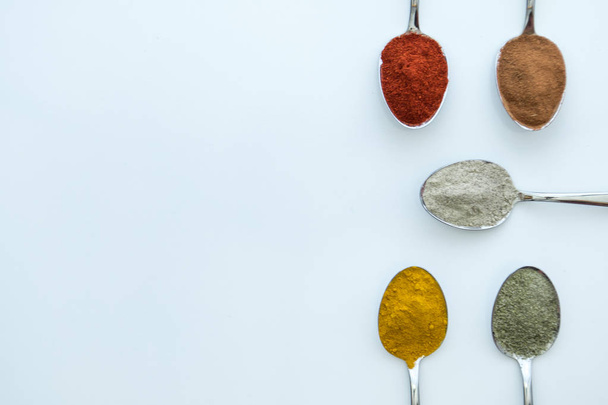 Erilaisia värikkäitä mausteita, jotka on järjestetty lusikoihin
  - Valokuva, kuva