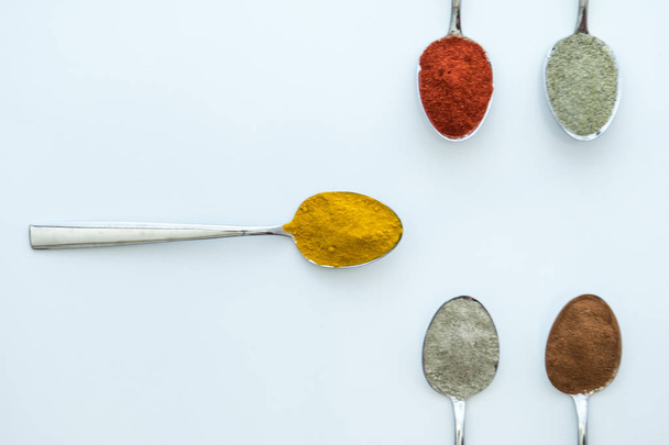 Various colorful spices arranged on spoons  - Fotó, kép