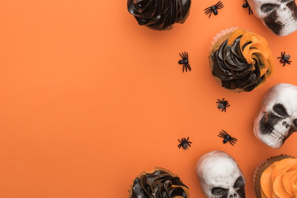 Widok z góry na pyszne Halloween Cupcakes z pająkami i czaszki na pomarańczowym tle z kopią przestrzeni - Zdjęcie, obraz
