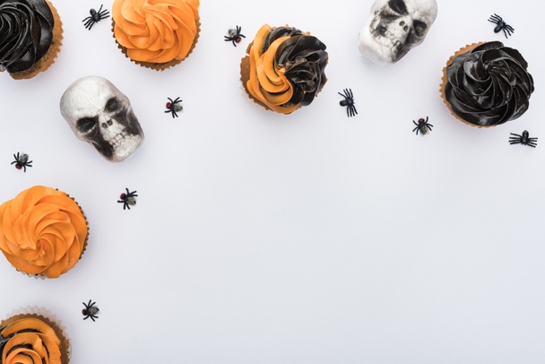 top view of Halloween cupcakes with spiders and skulls on white background with copy space - Foto, immagini