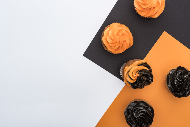 top view of delicious Halloween cupcakes on black, orange and white background with copy space - Photo, Image