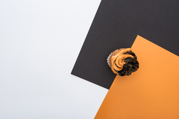 top view of delicious Halloween cupcake on orange, black and white background with copy space - 写真・画像