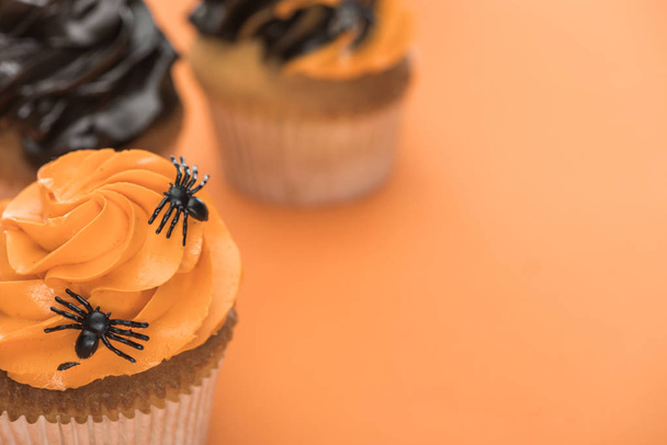 selective focus of scary Halloween cupcake with spiders on orange background - Foto, Imagen