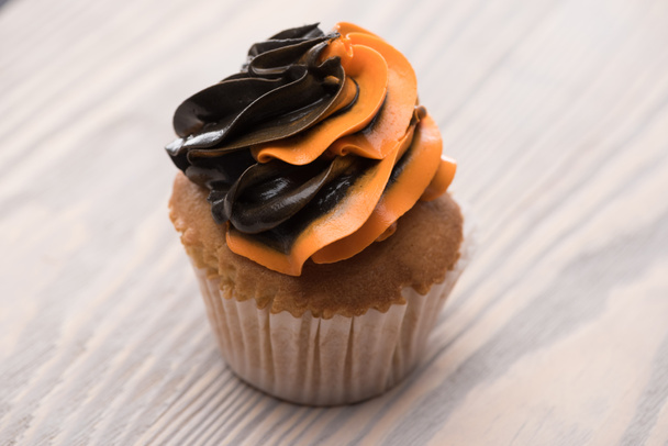 black and orange delicious Halloween cupcake on wooden table - Photo, Image