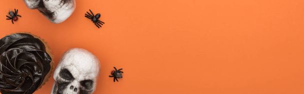вид сверху на кекс, декоративные черепа и пауков на оранжевом фоне с копировальным пространством, панорамный снимок
 - Фото, изображение