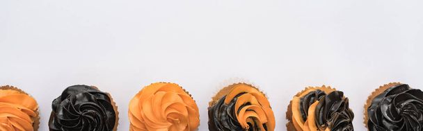 beyaz, panoramik çekim izole turuncu ve siyah lezzetli Halloween cupcakes üst görünümü - Fotoğraf, Görsel