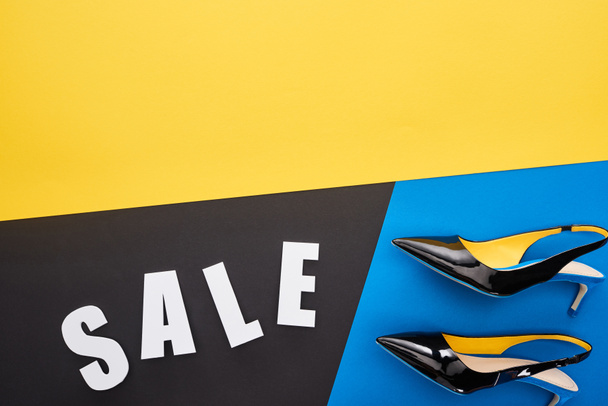top view of sale lettering near shoes on blue, yellow and black background - Photo, image
