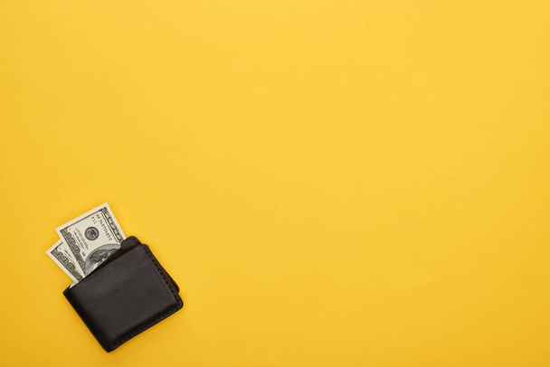 верхний вид бумажника с банкнотами доллара на желтом фоне
 - Фото, изображение